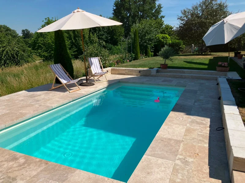 Travertin Pool mit Liegestühlen und Sonnenschirmen