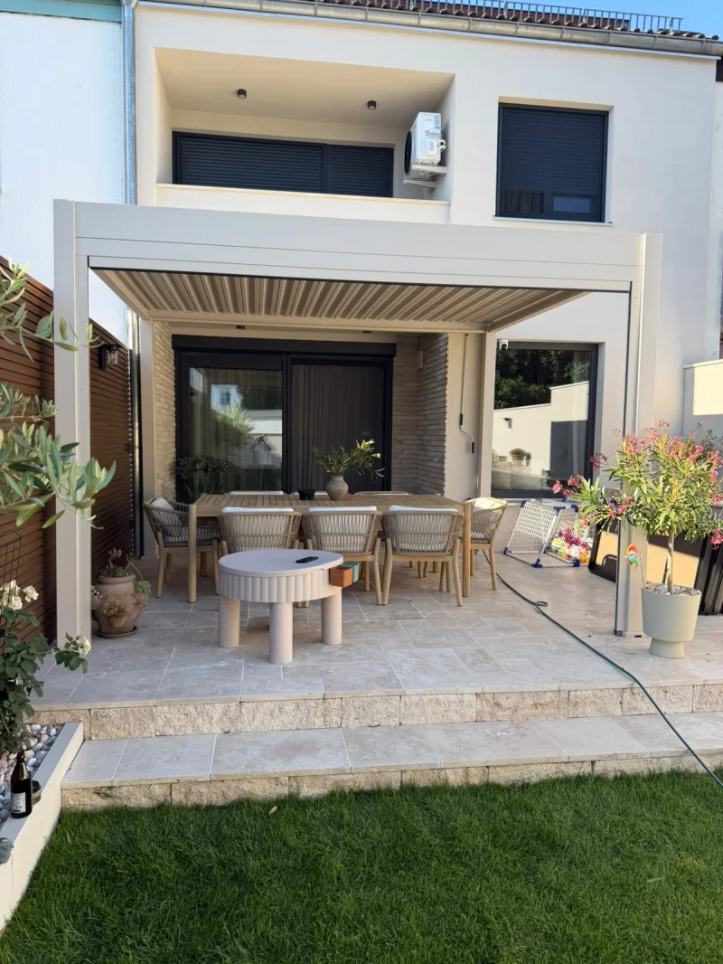 Überdachte Terrasse mit Travertin Bodenplatten, Esstisch und Lamellendach